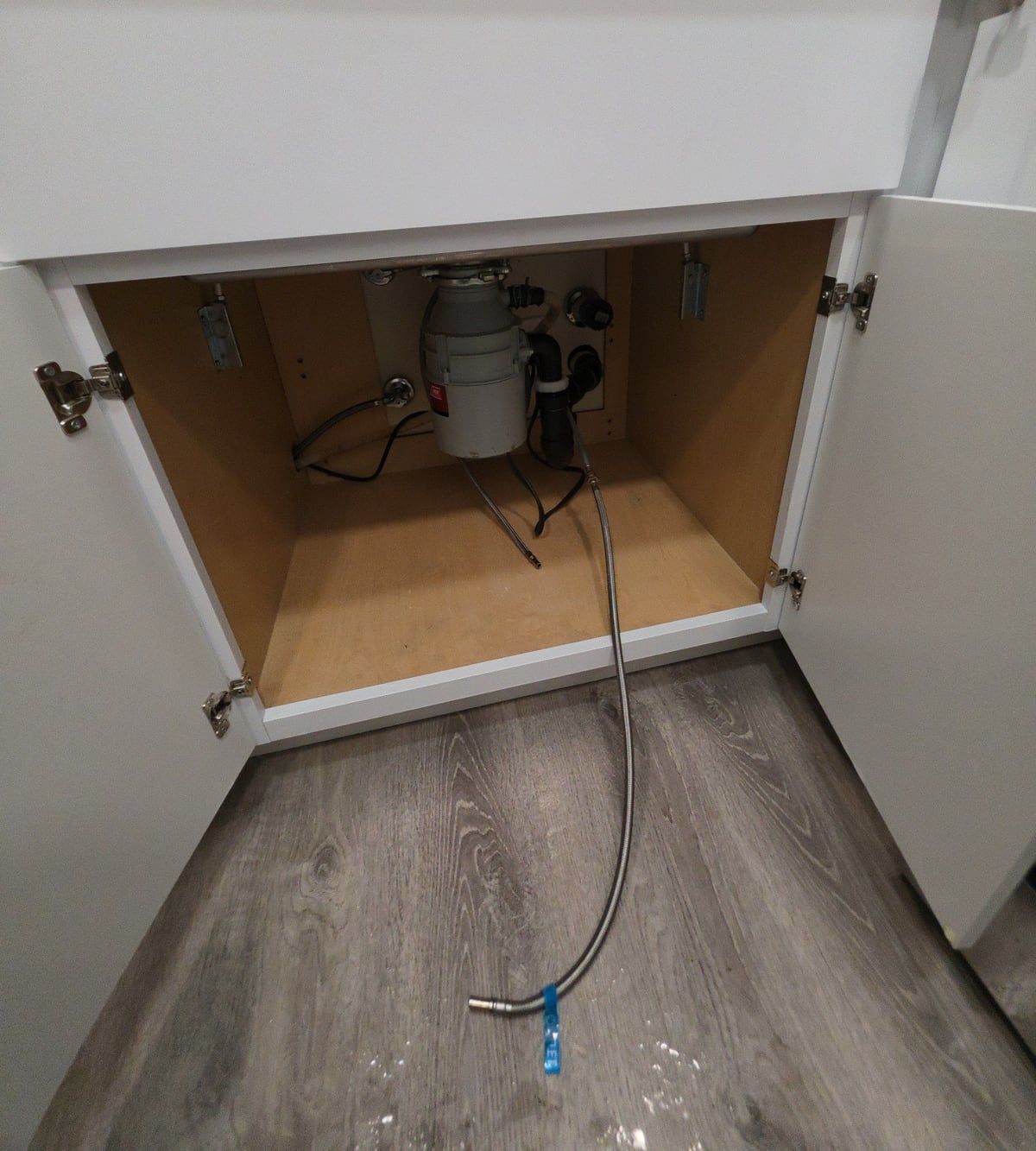 Open under-sink cabinet showing the disconnected water-filter supply line