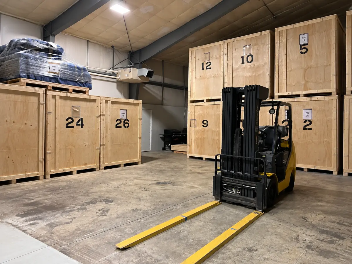 Forklift and wooden contents-storage vaults inside a restoration warehouse.